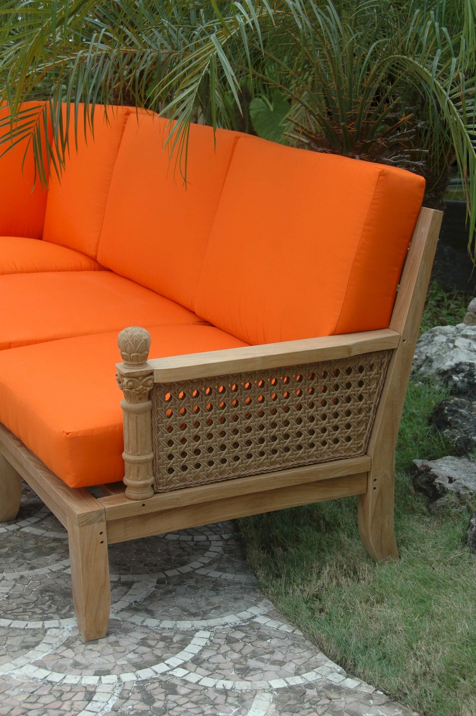 Orange cushioned outdoor sofa with wicker frame in a garden setting