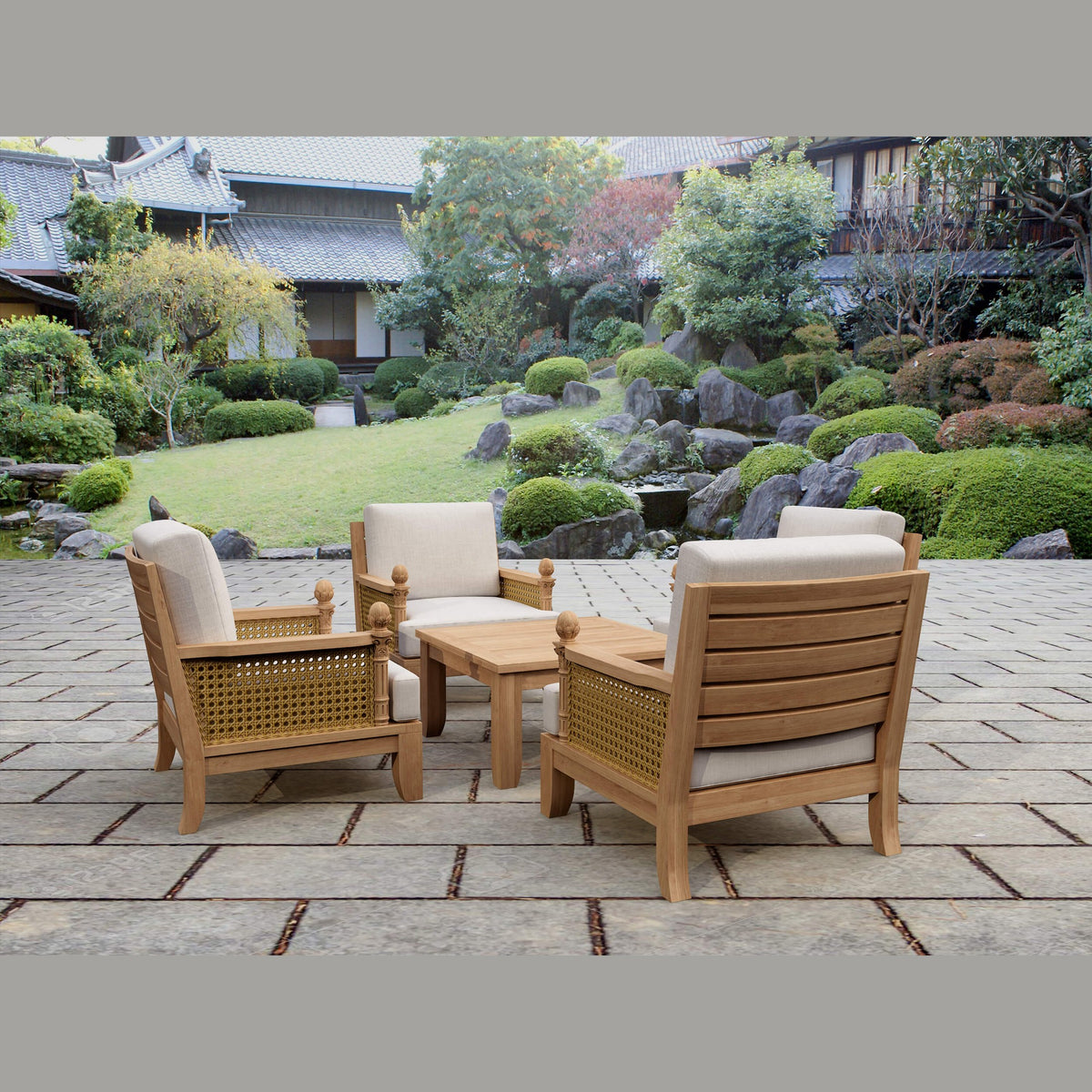 Outdoor furniture set with wooden chairs and table on a stone patio, garden in the background
