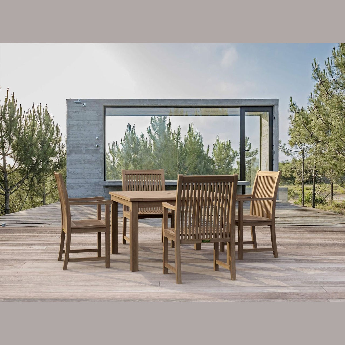 Outdoor dining set on a wooden deck with a modern building and trees in the background
