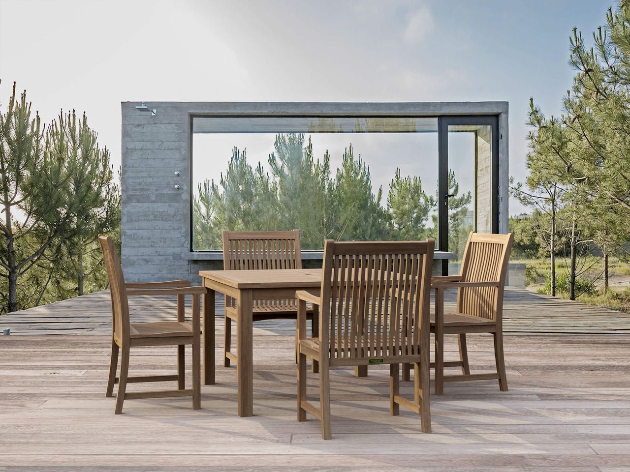 Outdoor dining set on a wooden deck with a modern building and trees in the background
