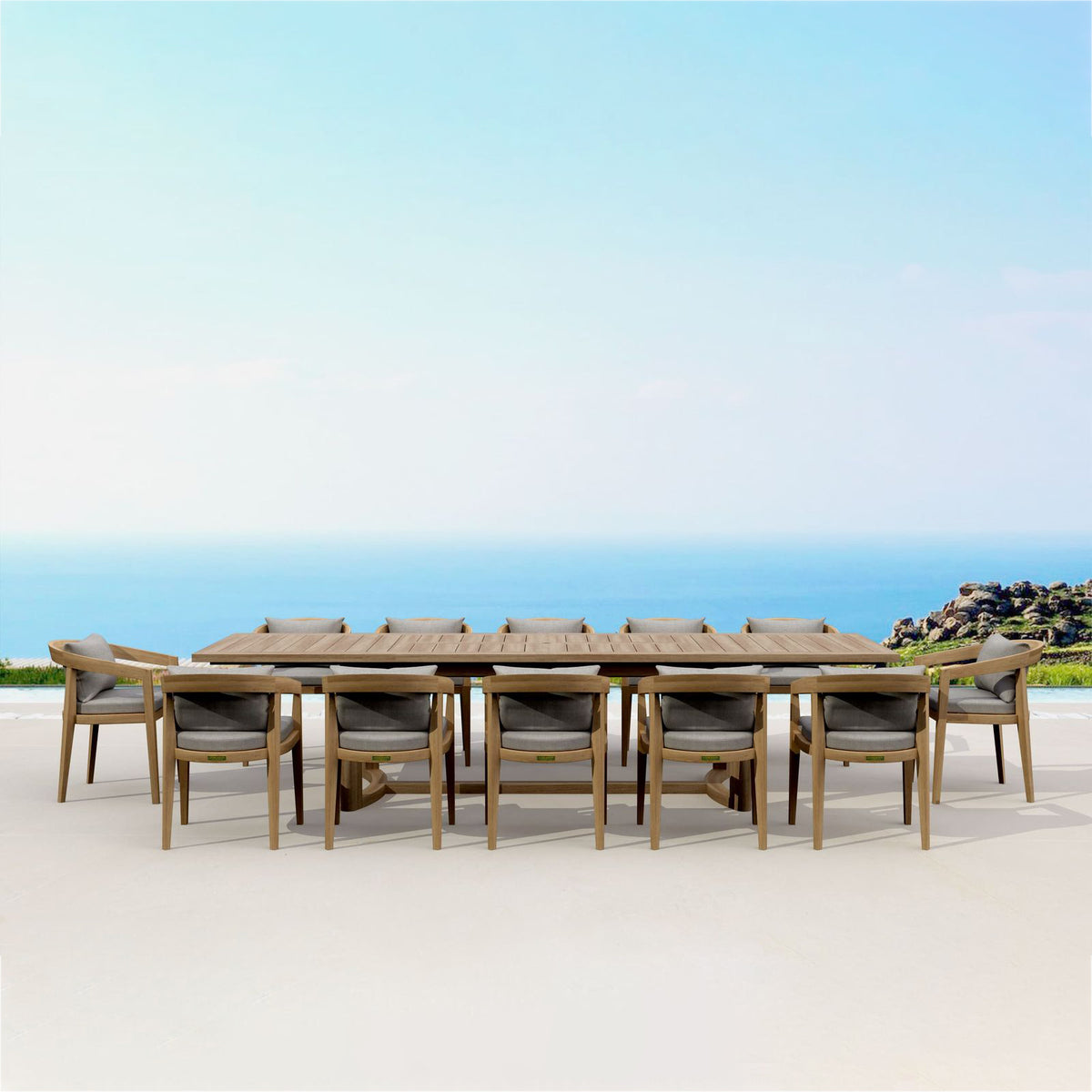 Outdoor dining set with a long table and chairs on a sandy beach with ocean view.