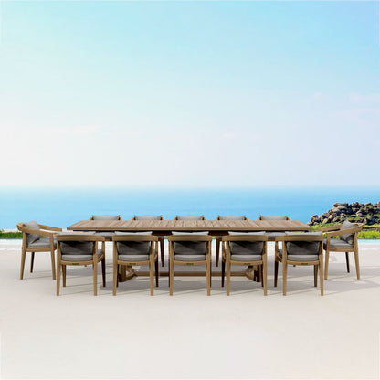 Outdoor dining set with a long table and chairs on a sandy beach with ocean view.