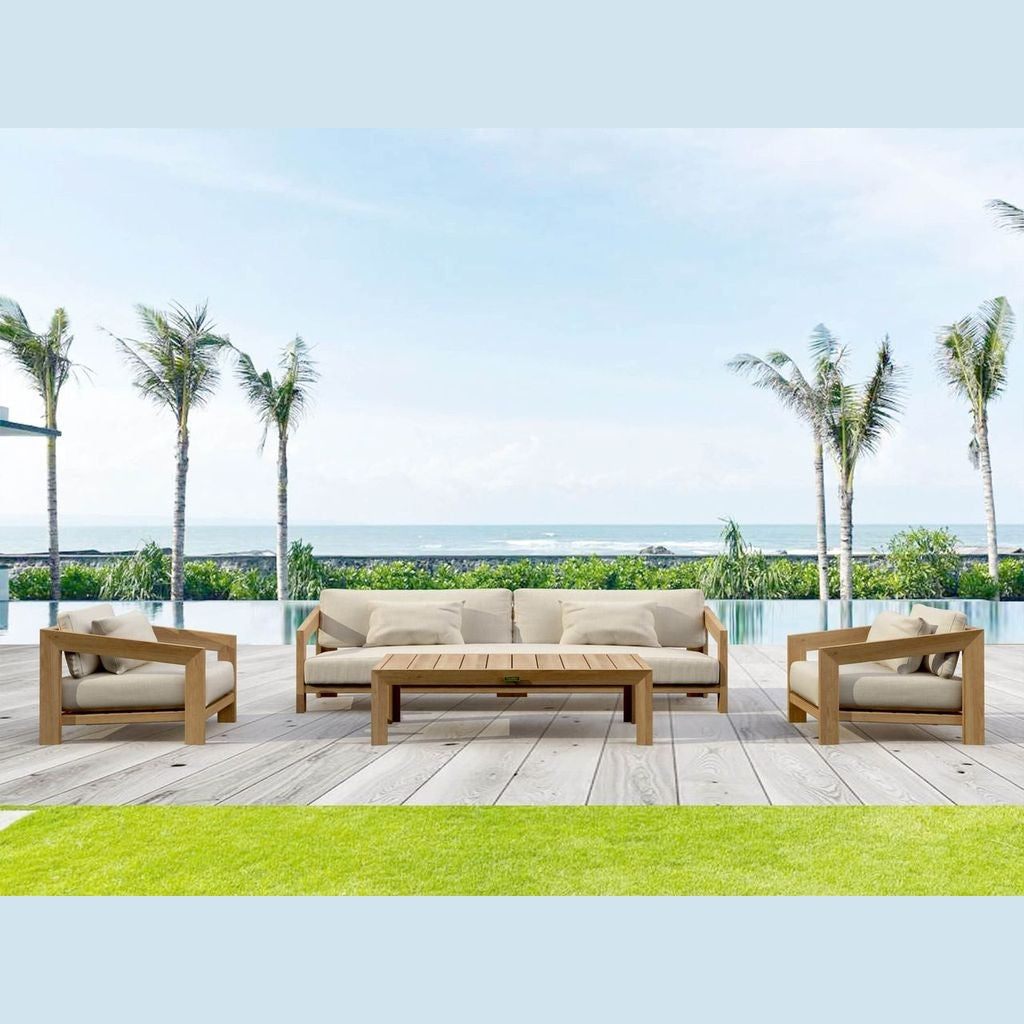Outdoor furniture set with beige cushions on a wooden deck by a pool with palm trees in the background.