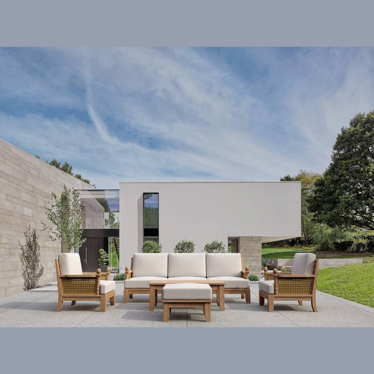 Outdoor patio set with sofa, chairs, and table in a modern garden setting.