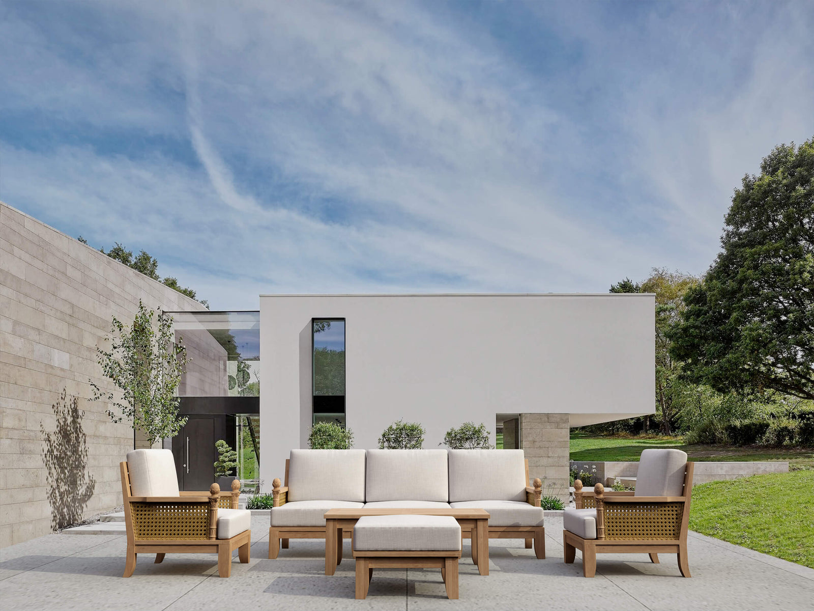 Outdoor patio set with sofa, chairs, and table in a modern garden setting.