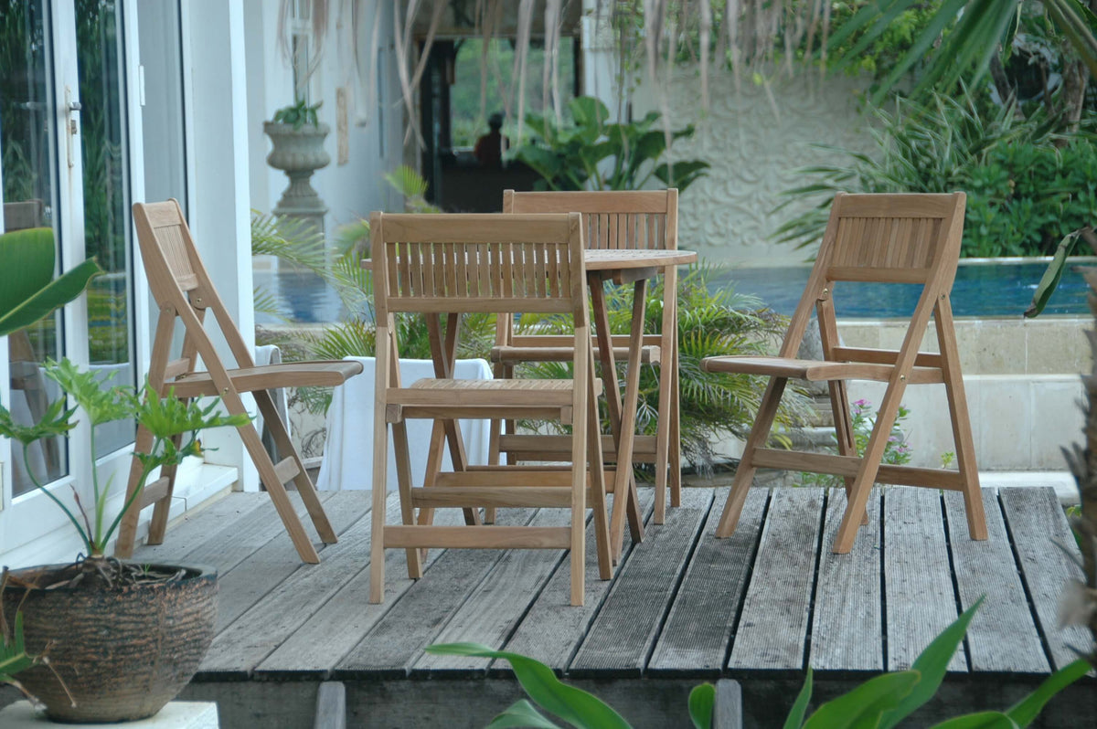 Wooden outdoor furniture set on a wooden deck with plants and a pool in the background