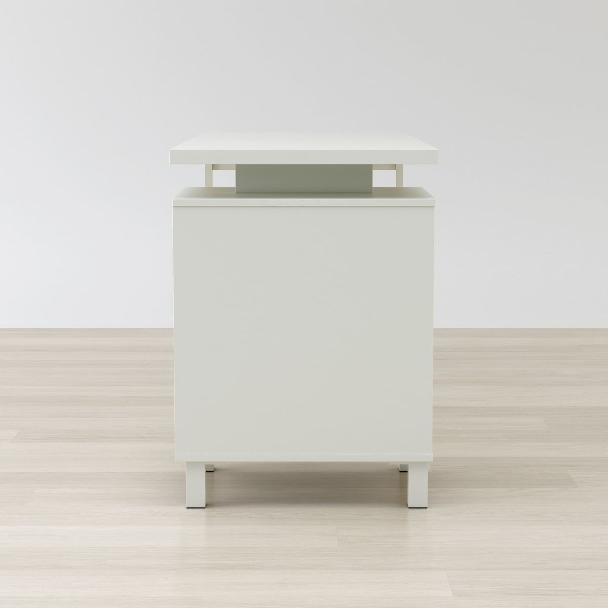White nightstand with a green accent on a wooden floor and white wall background