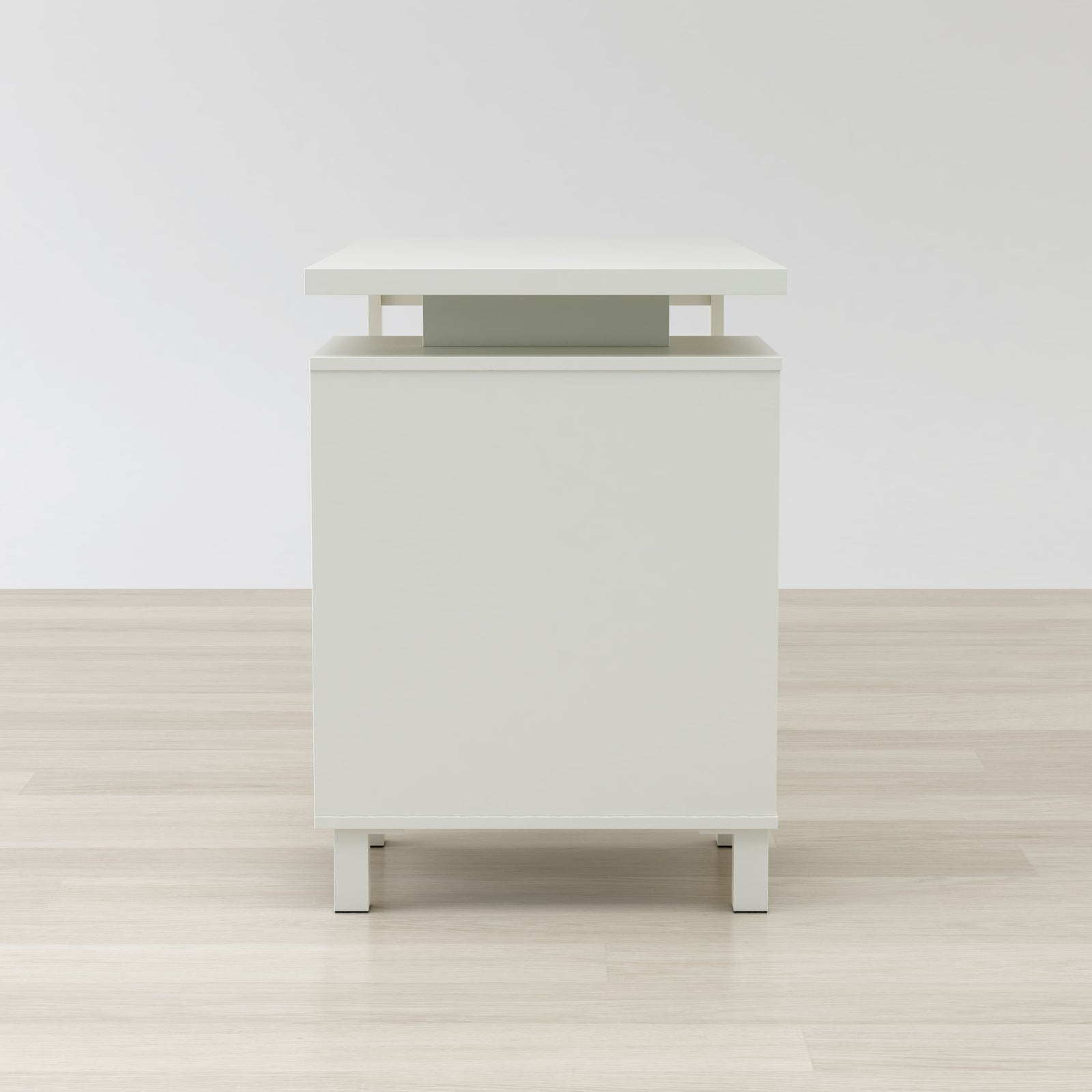White nightstand with a green accent on a wooden floor and white wall background