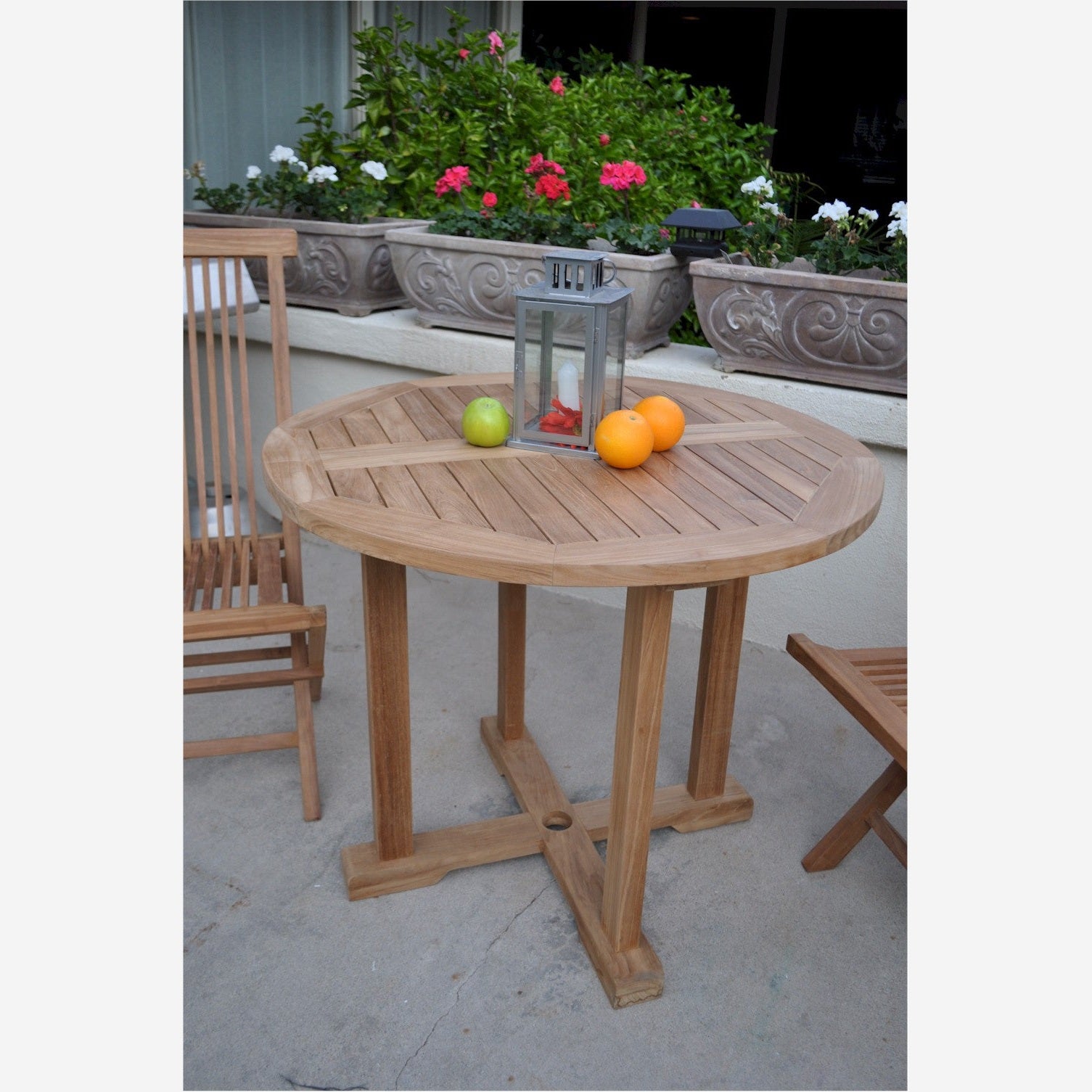 Wooden outdoor table with fruits and a lantern on a patio
