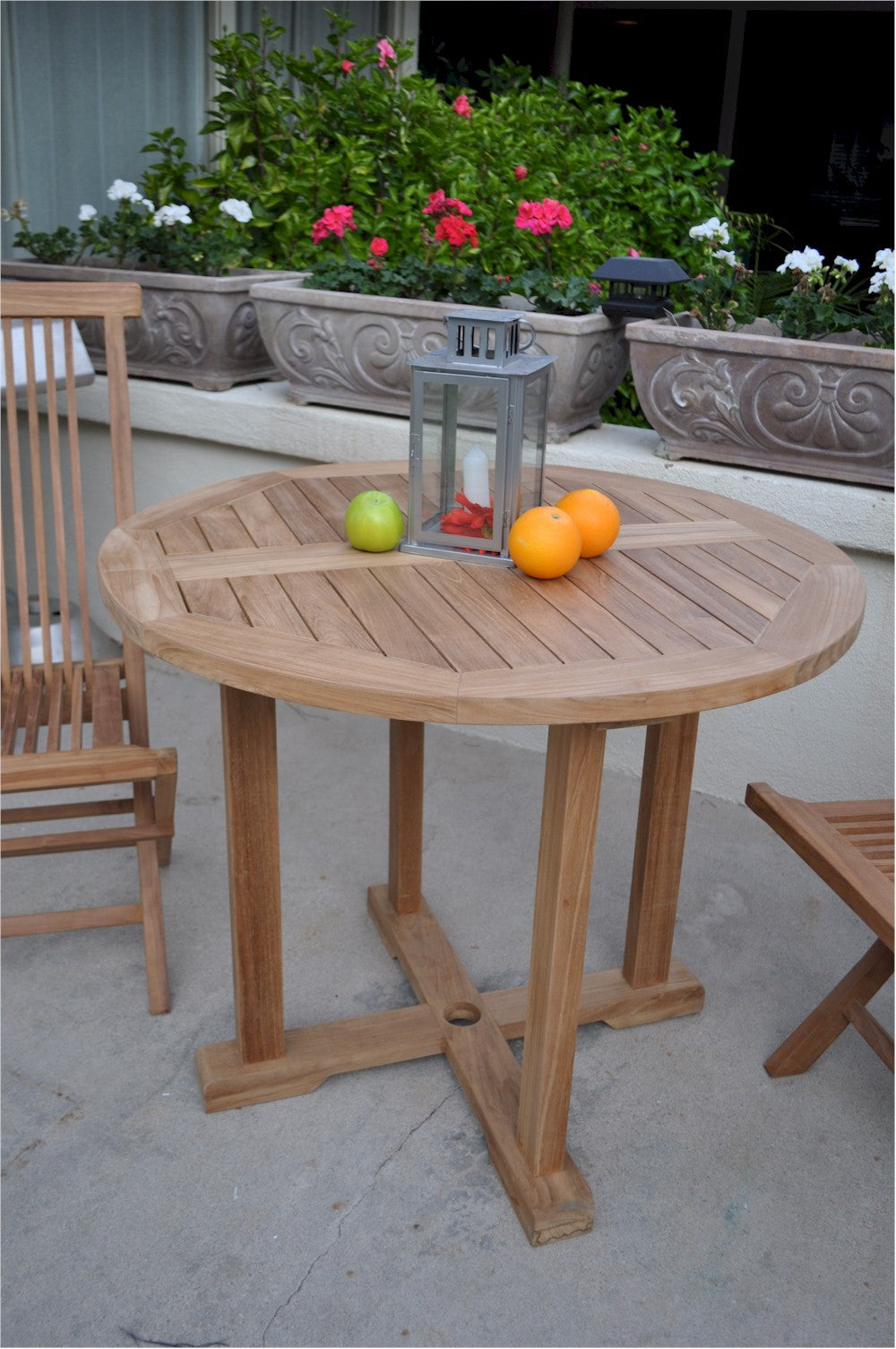 Wooden outdoor table with fruits and a lantern on a patio