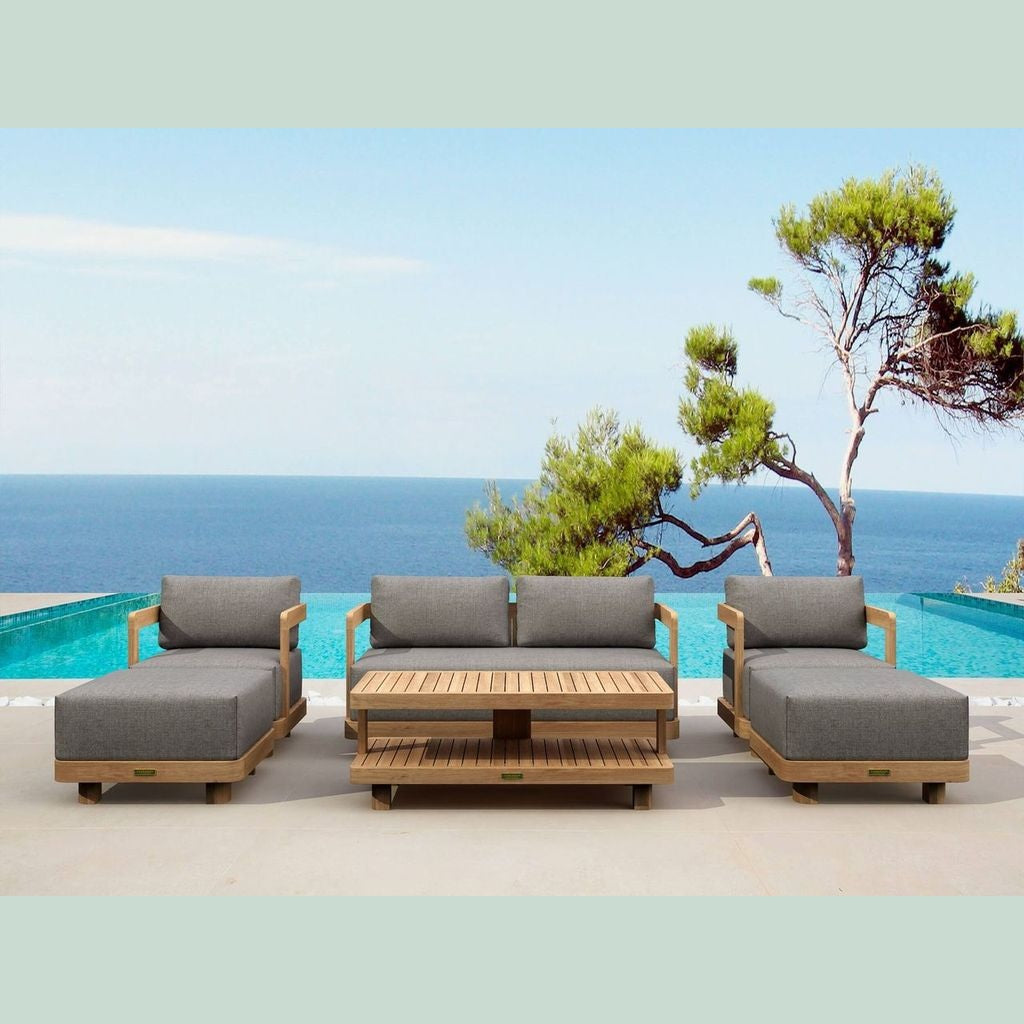 Outdoor patio furniture set with gray cushions by a pool and ocean view.