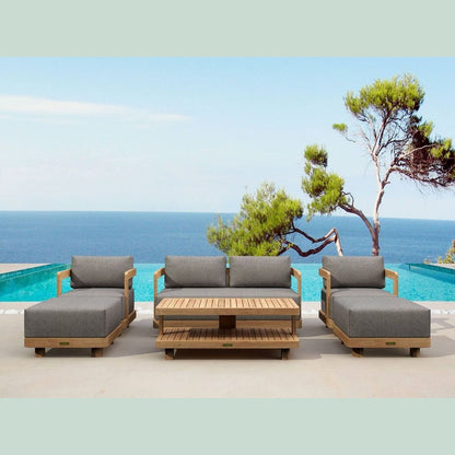 Outdoor patio furniture set with gray cushions by a pool and ocean view.
