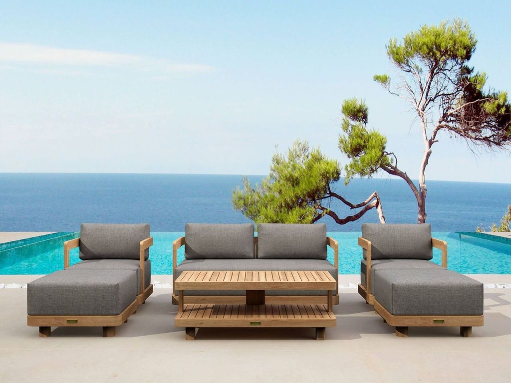 Outdoor patio furniture set with gray cushions by a pool and ocean view.