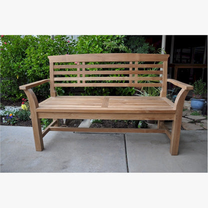 Wooden bench on a patio with greenery in the background