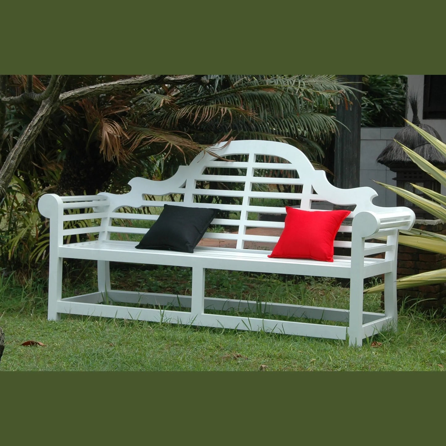 White garden bench with black and red cushions in a garden setting