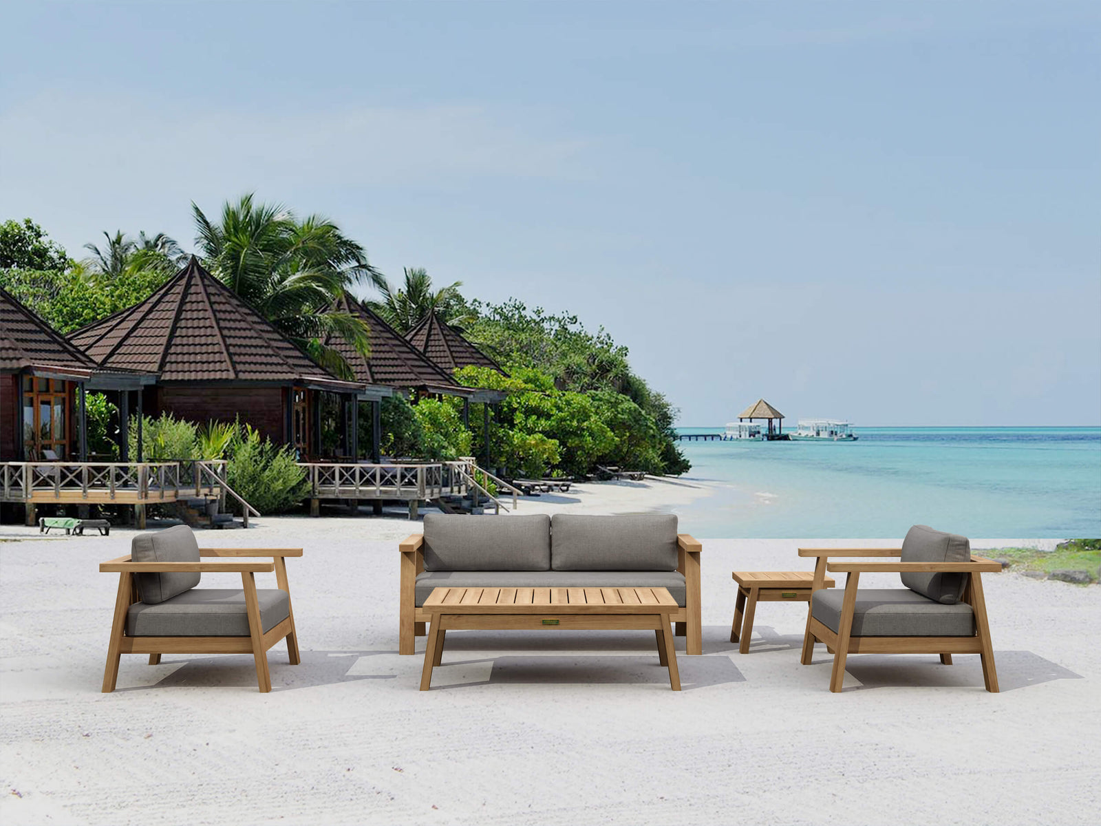 Outdoor furniture set on a sandy beach with ocean and tropical trees in the background