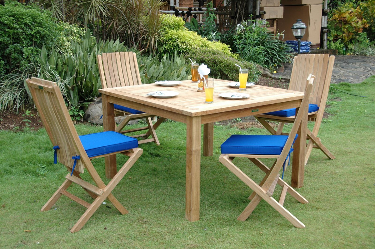 Outdoor wooden dining set with blue cushions on a grassy area
