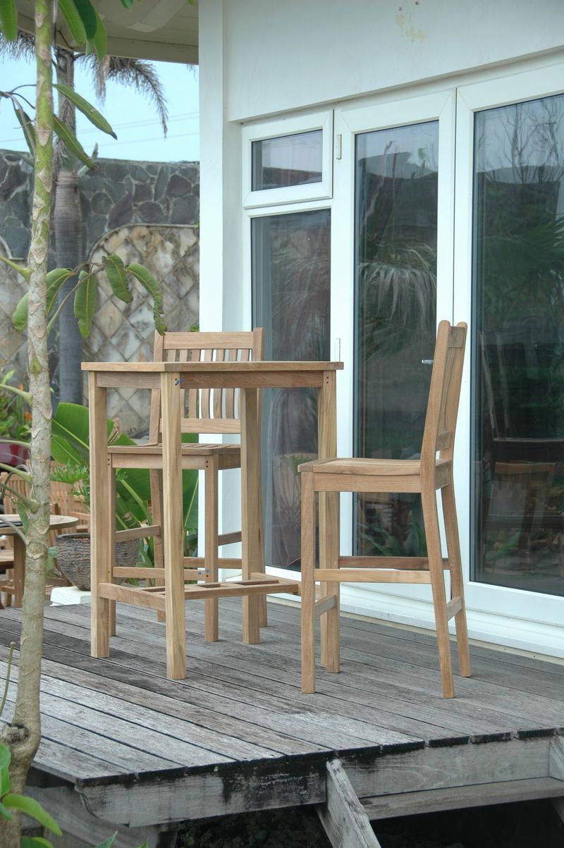 Wooden outdoor dining set on a wooden deck with a glass door in the background.