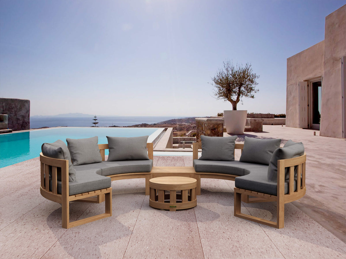 Outdoor patio set with wooden chairs and gray cushions by a pool with ocean view.