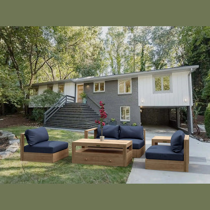 Outdoor patio set with wooden furniture and blue cushions in a backyard setting.