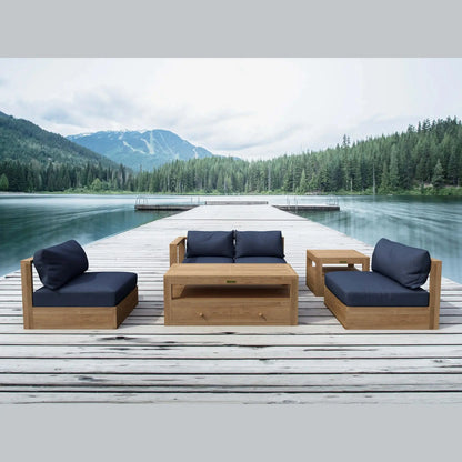 Outdoor wooden furniture set with blue cushions on a dock by a lake with mountains in the background