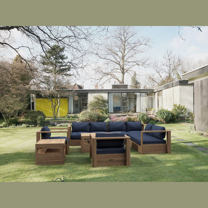 Outdoor wooden furniture set with blue cushions on a grassy lawn in front of a modern house.