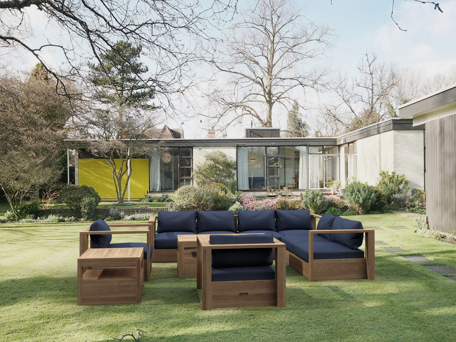 Outdoor wooden furniture set with blue cushions on a grassy lawn in front of a modern house.