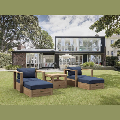 Outdoor furniture set with blue cushions on a grassy lawn in front of a modern house.