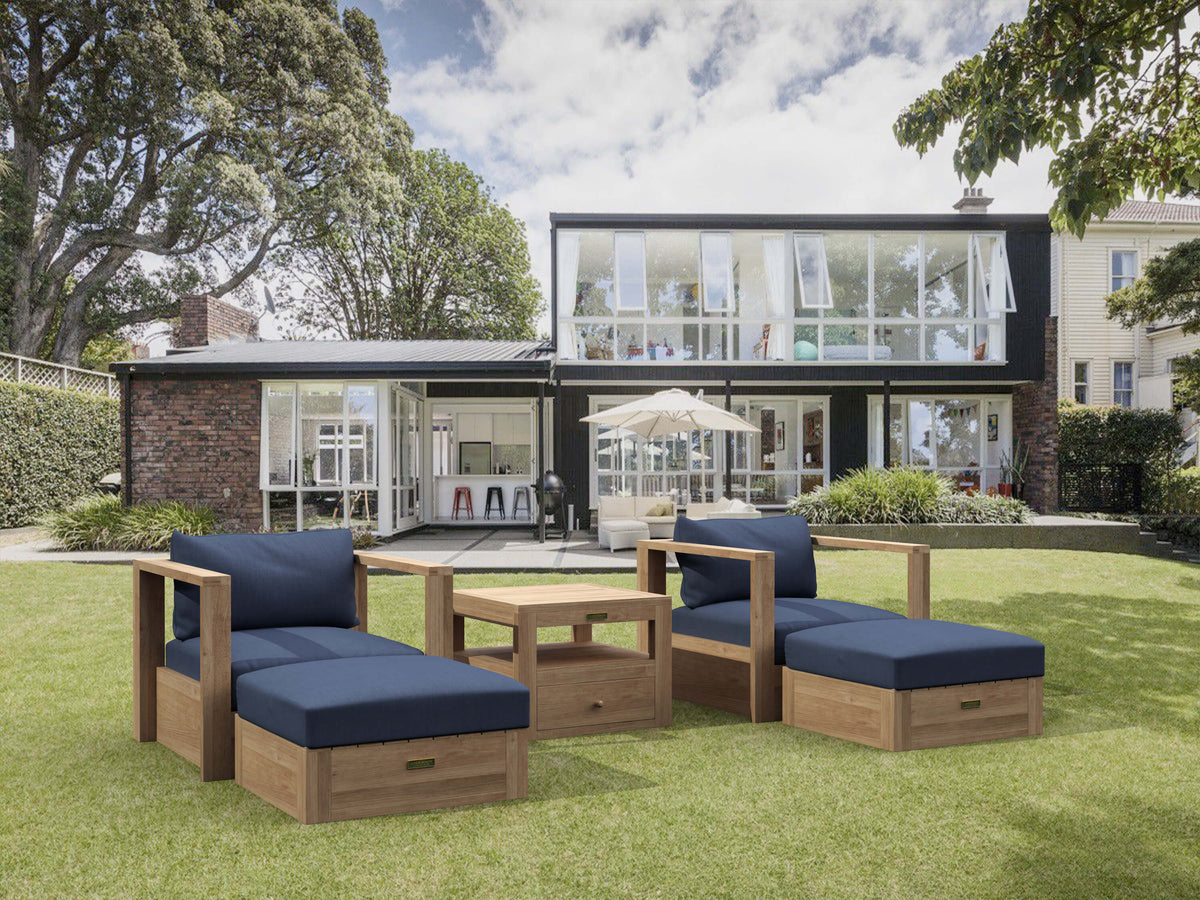 Outdoor furniture set with blue cushions on a grassy lawn in front of a modern house.