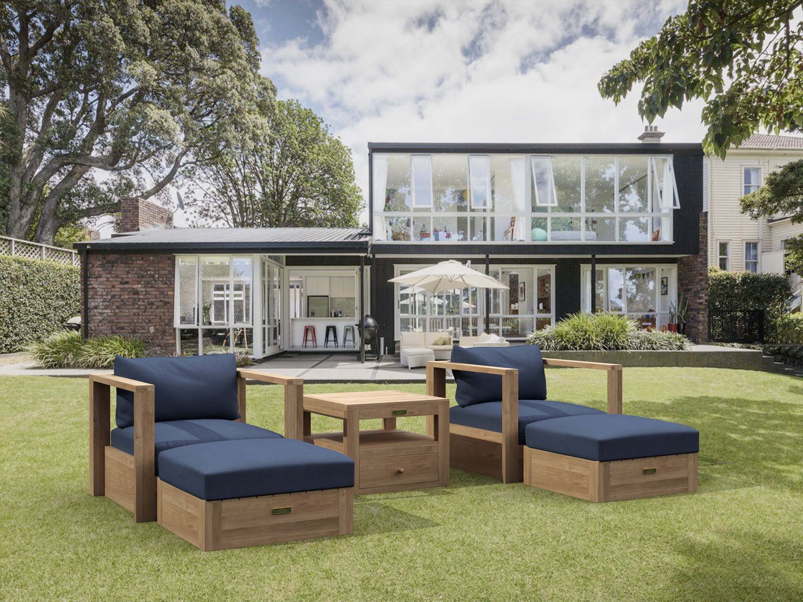 Outdoor furniture set with blue cushions on a grassy lawn in front of a modern house.