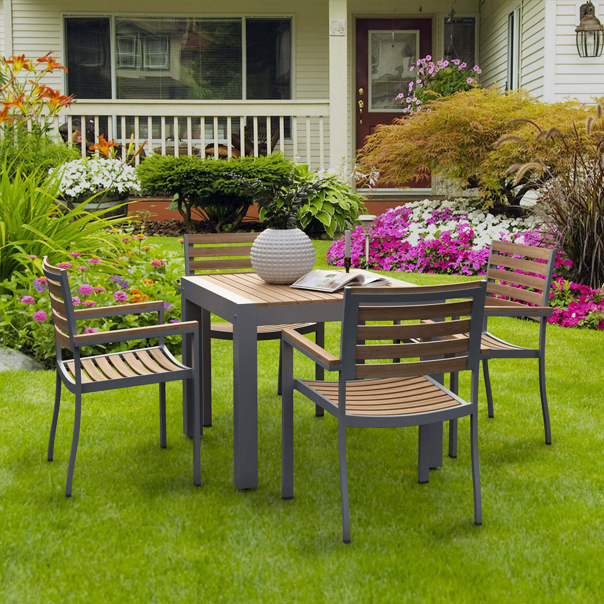 Outdoor patio set with table and chairs on a grassy lawn in front of a house.