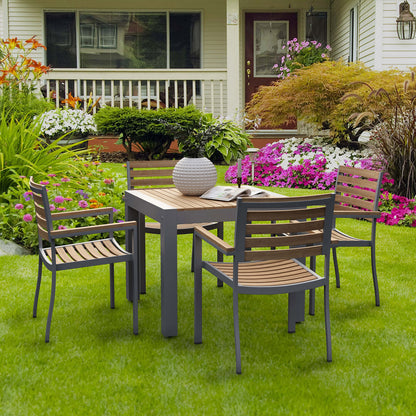 Outdoor patio set with table and chairs on a grassy lawn in front of a house.