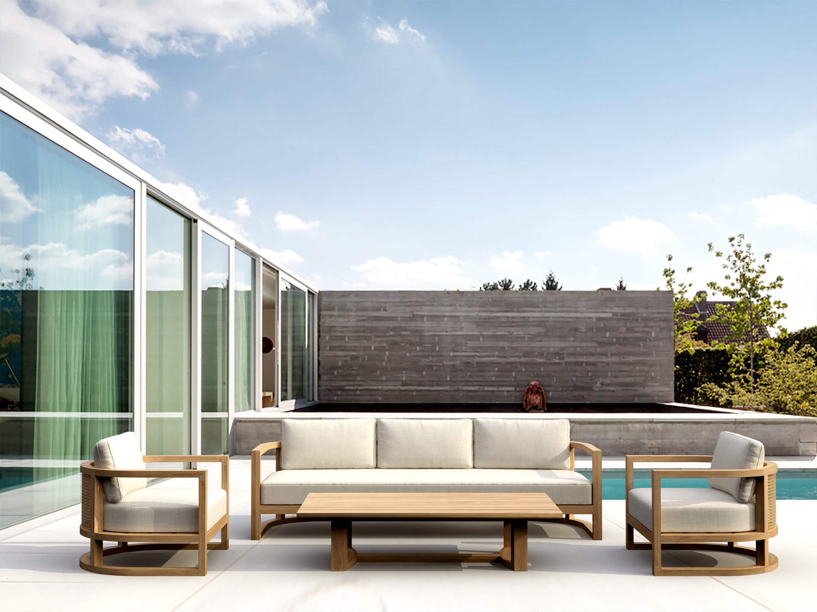 Outdoor patio set with sofa, chairs, and coffee table on a modern patio with pool and glass walls.