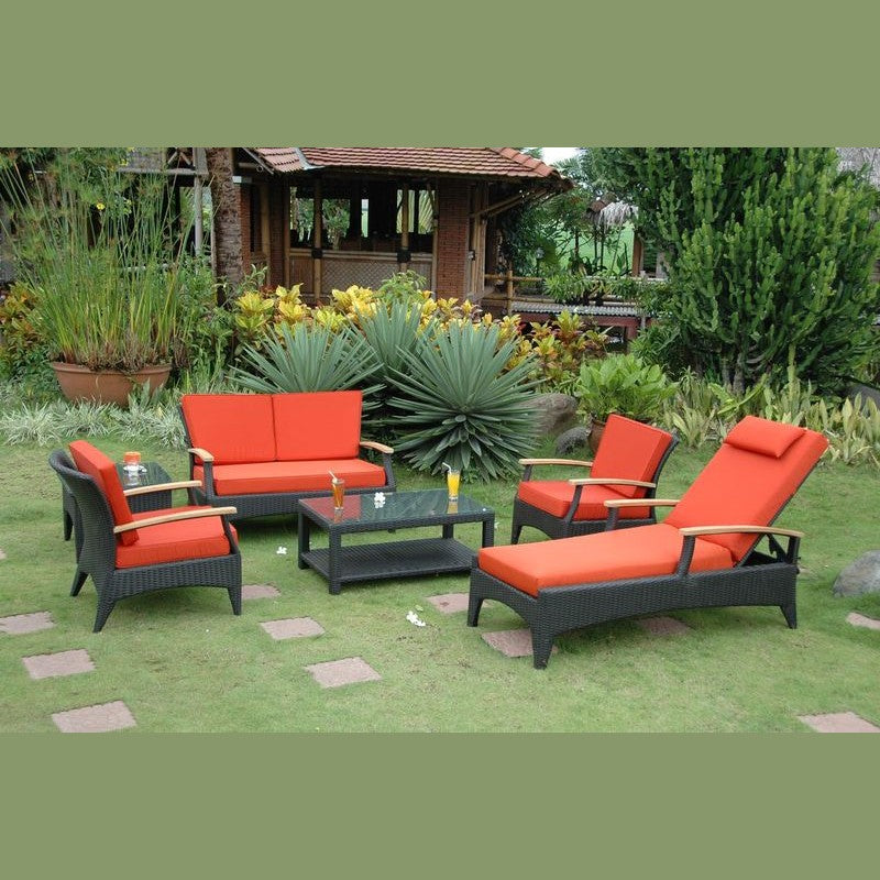 Outdoor patio set with red cushions on a grassy area with plants and a gazebo in the background.