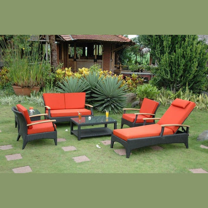 Outdoor patio set with red cushions on a grassy area with plants and a gazebo in the background.