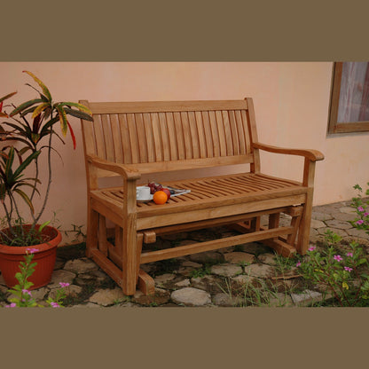 Wooden bench outdoors with a potted plant and flowers in the foreground.