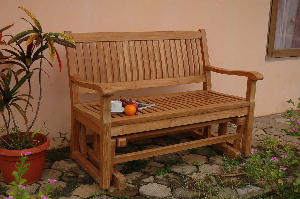 Wooden bench outdoors with a potted plant and flowers in the foreground.