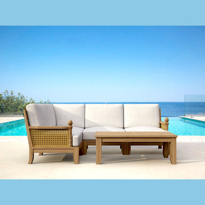 Outdoor patio set with a sofa and table by a pool with a clear blue sky.