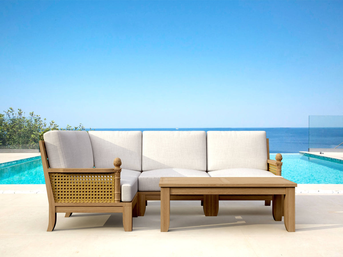 Outdoor patio set with a sofa and table by a pool with a clear blue sky.