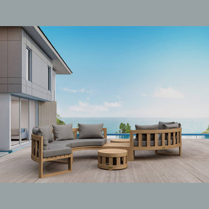 Outdoor wooden furniture set with gray cushions on a deck with a view of the ocean.
