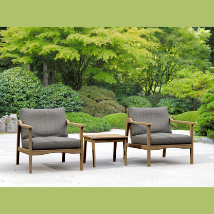 Two gray cushioned chairs with wooden frames and a matching table in a garden setting.