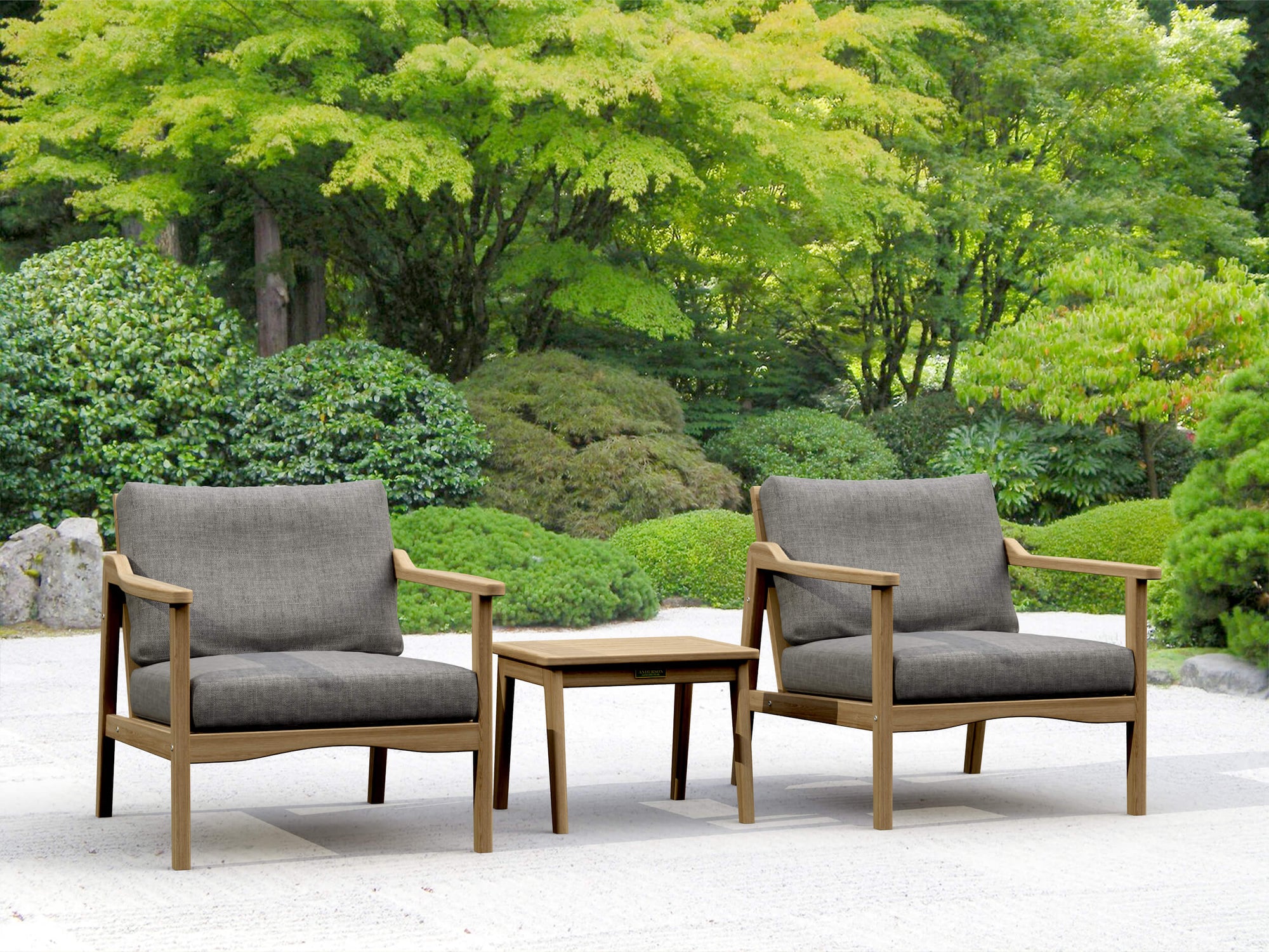 Two gray cushioned chairs with wooden frames and a matching table in a garden setting.