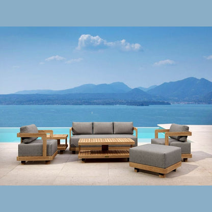 Outdoor furniture set with gray cushions and wooden frames by a scenic waterfront.