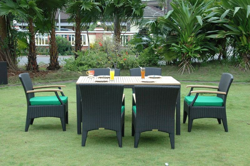 Outdoor furniture set with a table and chairs on a grassy area with trees in the background