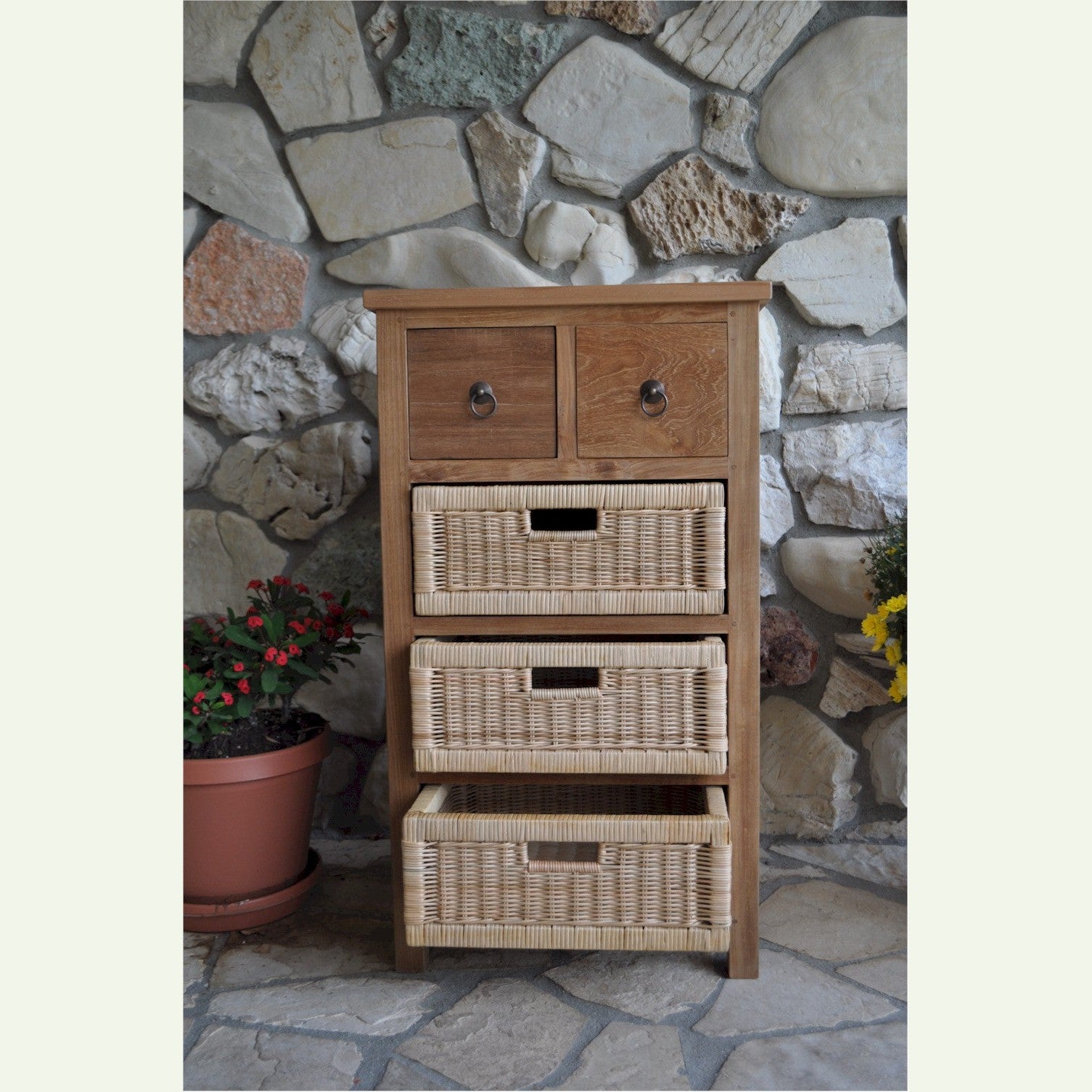 Wooden dresser with wicker drawers against a stone wall