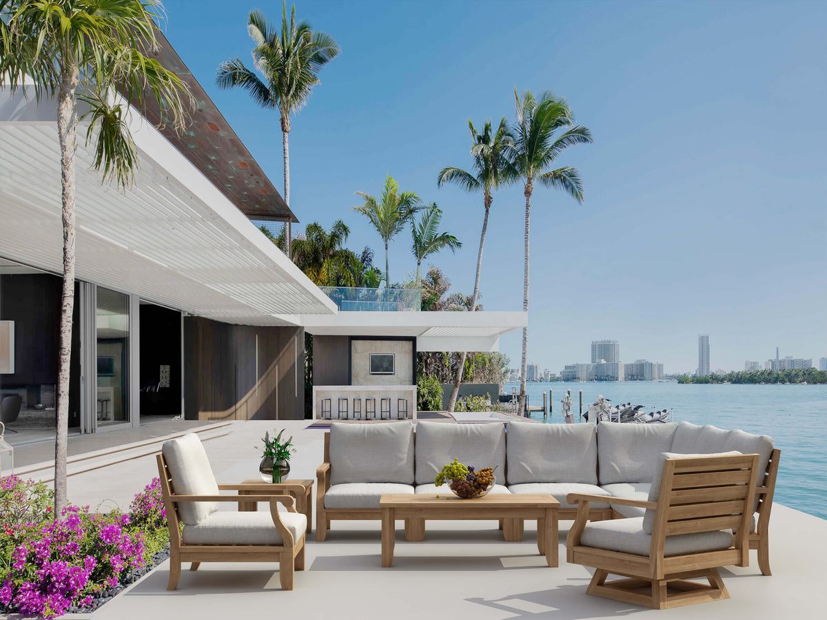 Outdoor patio with furniture and palm trees by a waterfront.