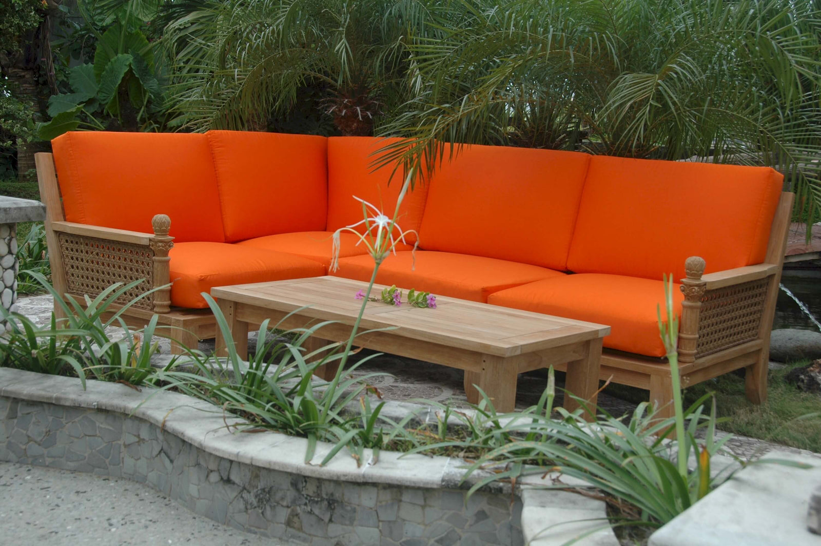 Orange outdoor sofa set with wooden coffee table in a garden setting
