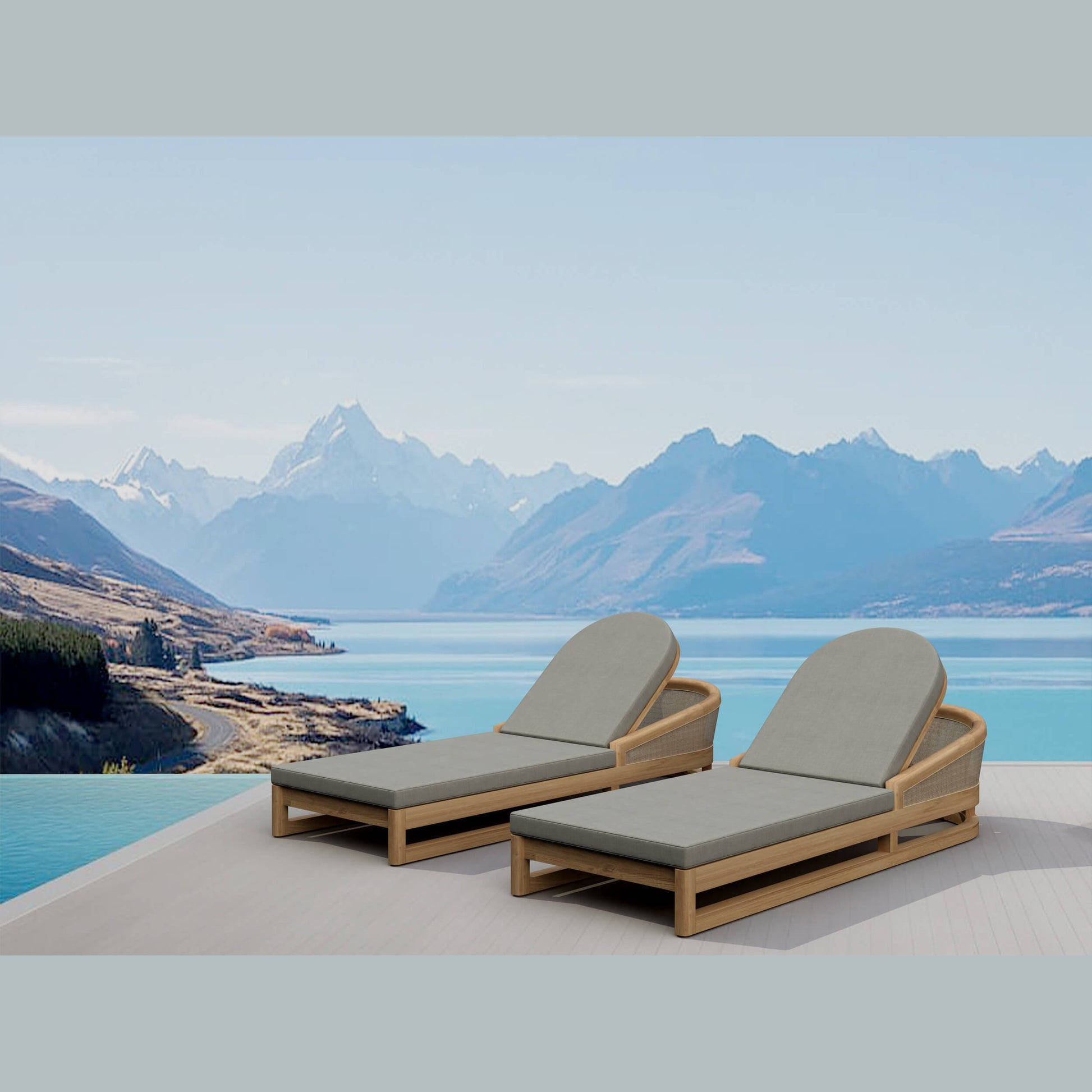 Two lounge chairs with gray cushions on a deck overlooking a lake and mountains.