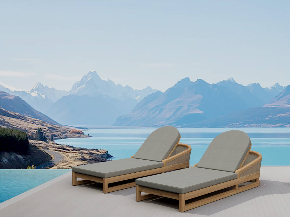 Two lounge chairs with gray cushions on a deck overlooking a lake and mountains.