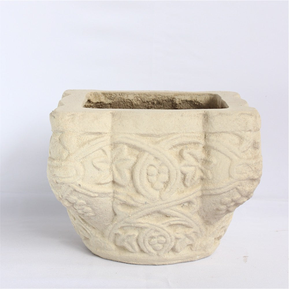 Decorative stone planter with intricate patterns on a white background